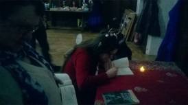 Halo Quin, with pixie ears and knitted wings, signing a copy of her book by candlelight.